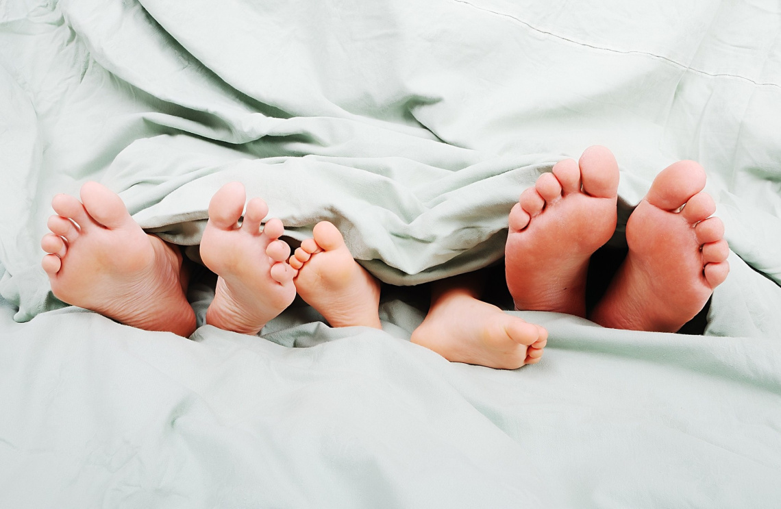 Семья в кровати с ребенком ноги